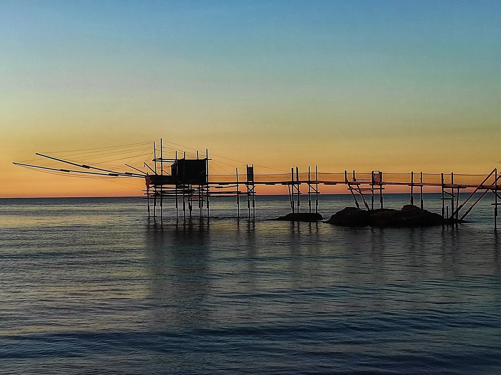 Un trabocco in legno sospeso sul mare al tramonto